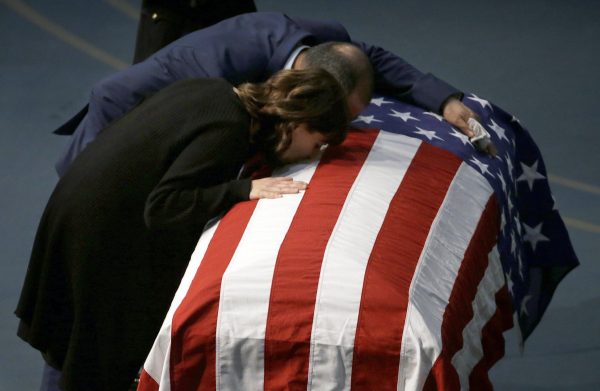 Lupe Corona and Merced Corona kiss the flag draped coffin of their daughter
