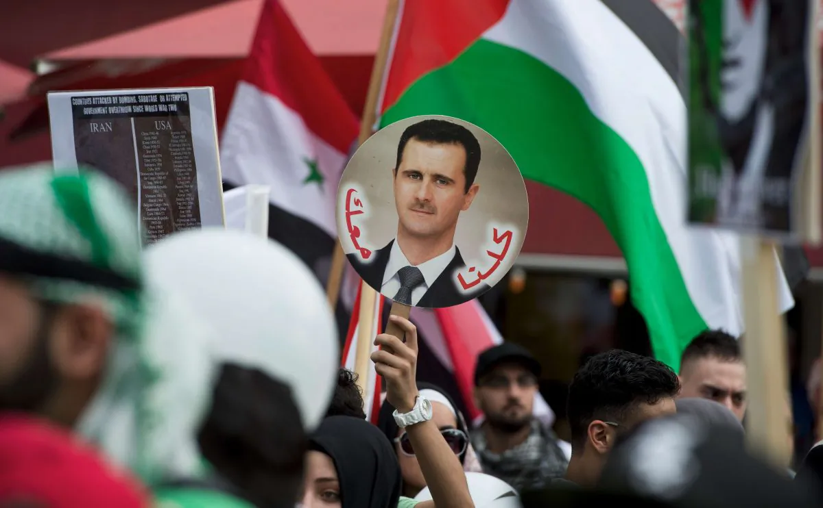 A demonstrator displays a placard featuring a portrait of Syrian President Bashar al-Assad during a rally in Berlin on Aug. 3, 2013. (John Macdougall/AFP/Getty Images)