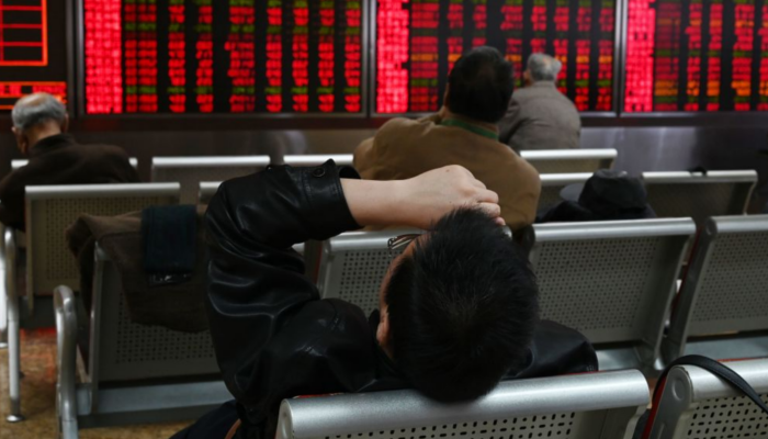 A man rests in front of screens showing stock prices at a securities company in Beijing on Jan. 21, 2019. (GREG BAKER/AFP/Getty Images)