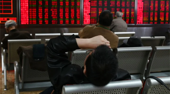 A man rests in front of screens showing stock prices at a securities company in Beijing on Jan. 21, 2019. (GREG BAKER/AFP/Getty Images)
