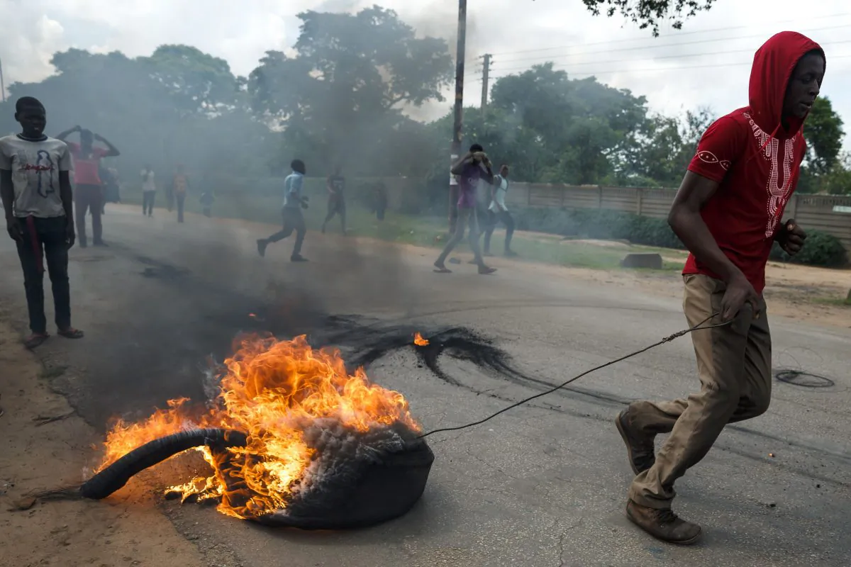 A man drags a burning tire as angry protesters barricade the main route to Zimbabwe's capital Harare from Epworth township on Jan. 14, 2019. (Jekesai Njikizana/AFP/Getty Images)