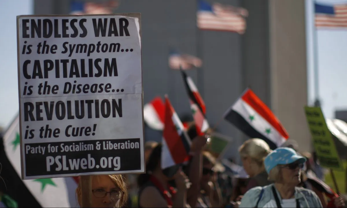A Socialist Party supporter holds a protest sign at a rally to urge Congress to vote against a limited military strike. Photo by David McNew/Getty Images
