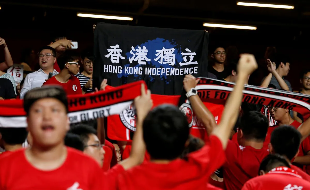 Football Soccer—Hong Kong v Malaysia —AFC Asian Cup Qualifiers in Hong Kong, China on Oct. 10, 2017. Hong Kong fans hold a protest banner and turn their backs during the Chinese national anthem. (Bobby Yip/Reuters)