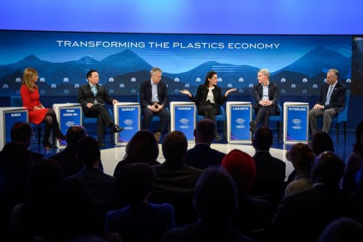 panel of speakers sitting onstage with blue background at davos