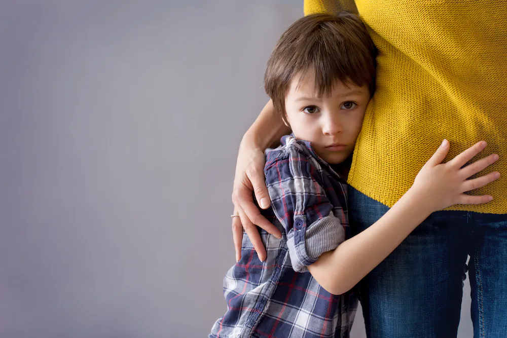 Sad little boy hugging his mother. (Shutterstock)