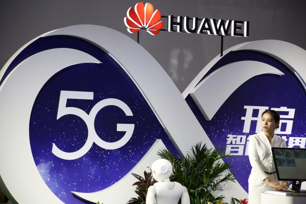 Woman stands at the booth of Huawei featuring 5G technology