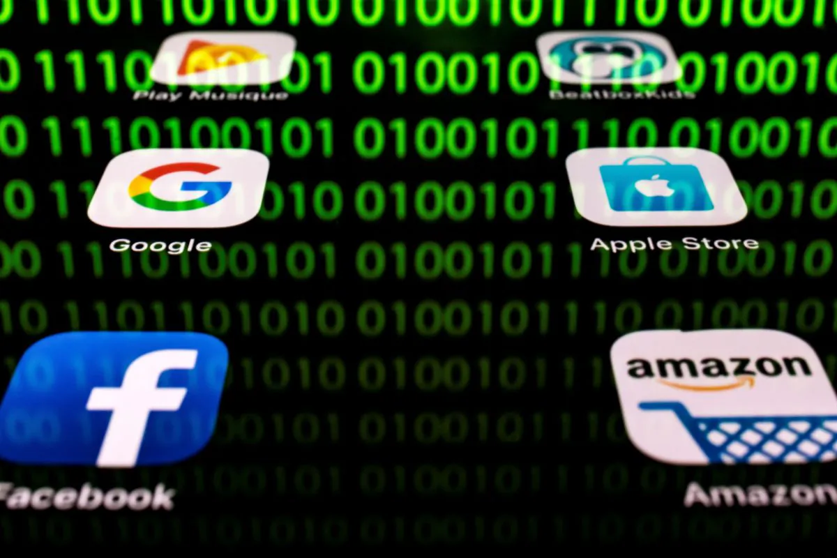 This illustration picture taken on April 20, 2018 in Paris shows apps for Google, Amazon, Facebook, Apple (GAFA) and the reflexion of a binary code displayed on a tablet screen. (Lionel Bonaventure/AFP/Getty Images)