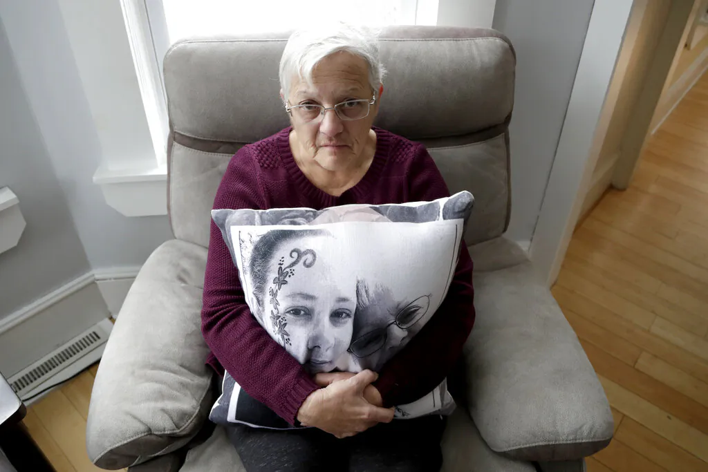 In a photo taken Friday, Jan. 18, 2019, Deborah Fuller poses for a photograph for The Associated Press with a pillow showing a photo of her late daughter, Sarah Fuller, left, who passed of a prescription drug overdose, and her during an interview in her home in West Berlin, N.J. The trial of the Insys Therapeutics Inc. founder John Kapoor, who accused of scheming to bribe doctors into prescribing a powerful painkiller, is putting a spotlight on the nation's deadly opioid crisis. (AP Photo/Julio Cortez)