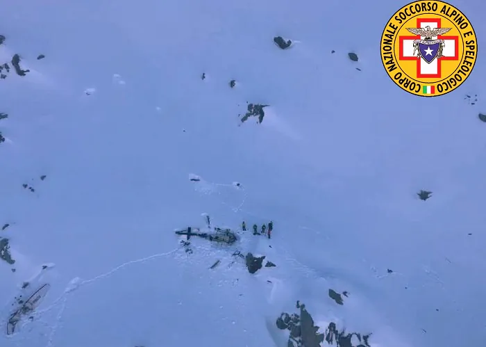 Rescuers stand next to the debris of an helicopter after a midair collision between a small tourist airplane and a helicopter carrying skiers to a glacier in the northwestern region of Val d'Aosta,, on Jan. 25, 2019. (Soccorso Alpino e Speleologico via AP)