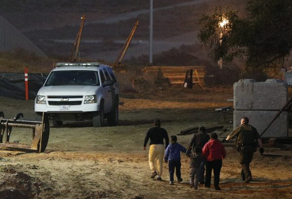 Migrants are escorted by a U.S. Border Patrol agent