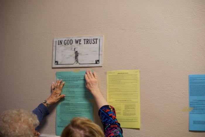 In God We Trust plaque above voting notices.