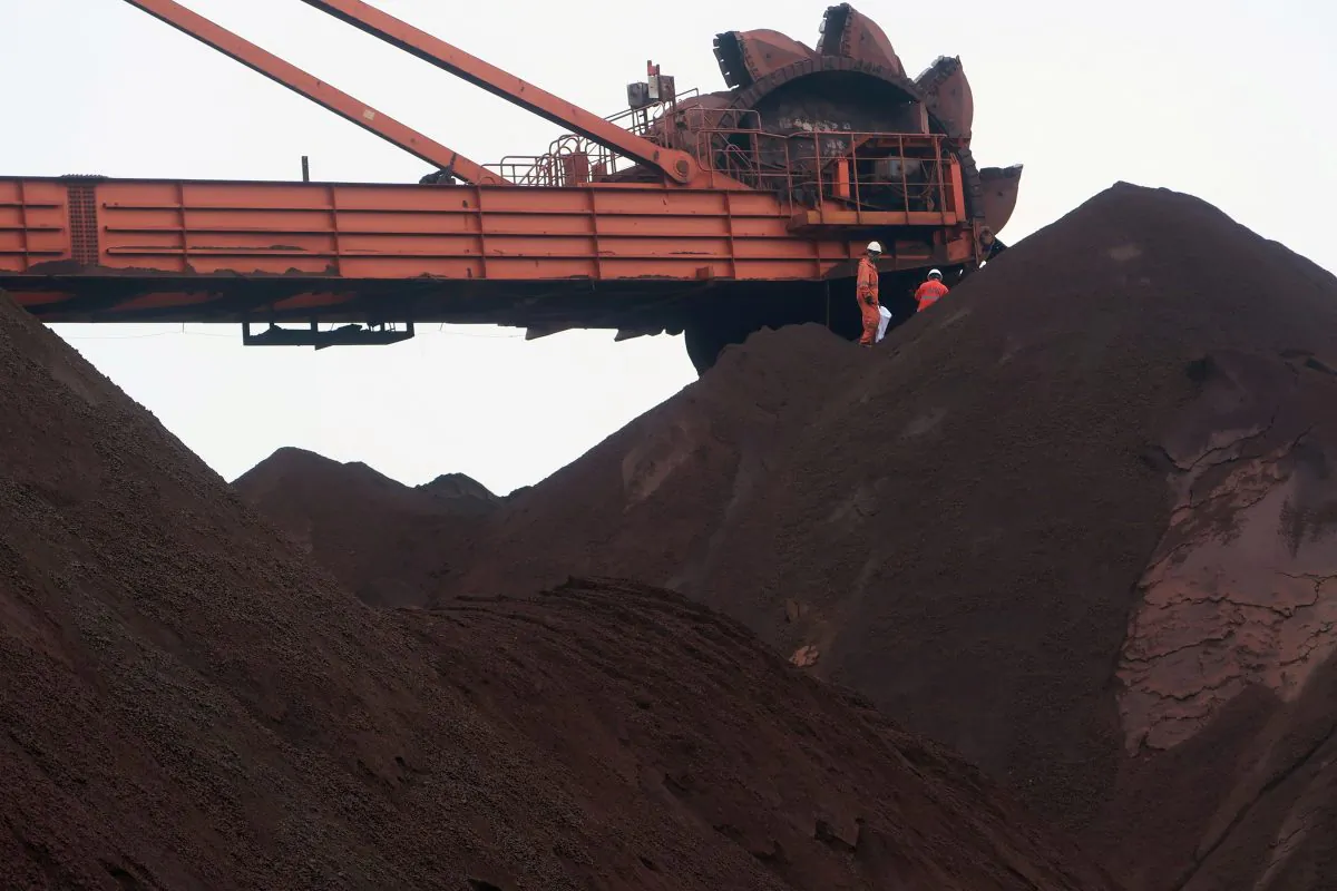 Workers are seen on the top of an iron ore pile as a machine works on blending the iron ore, at Dalian Port, Liaoning Province, China on Sept. 21, 2018. (Muyu Xu/Reuters)