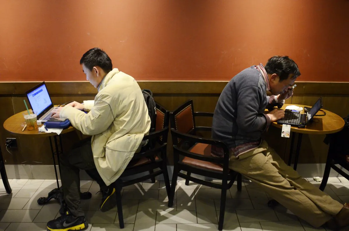 Two Chinese men use their laptop computers at a cafe in Beijing on Nov. 2, 2012. A government-backed campaign to assert greater control over social media has lead to increased self-censorship by some of China's most influential bloggers, chilling political discourse in the country. (Wang Zhao/AFP/Getty Images)