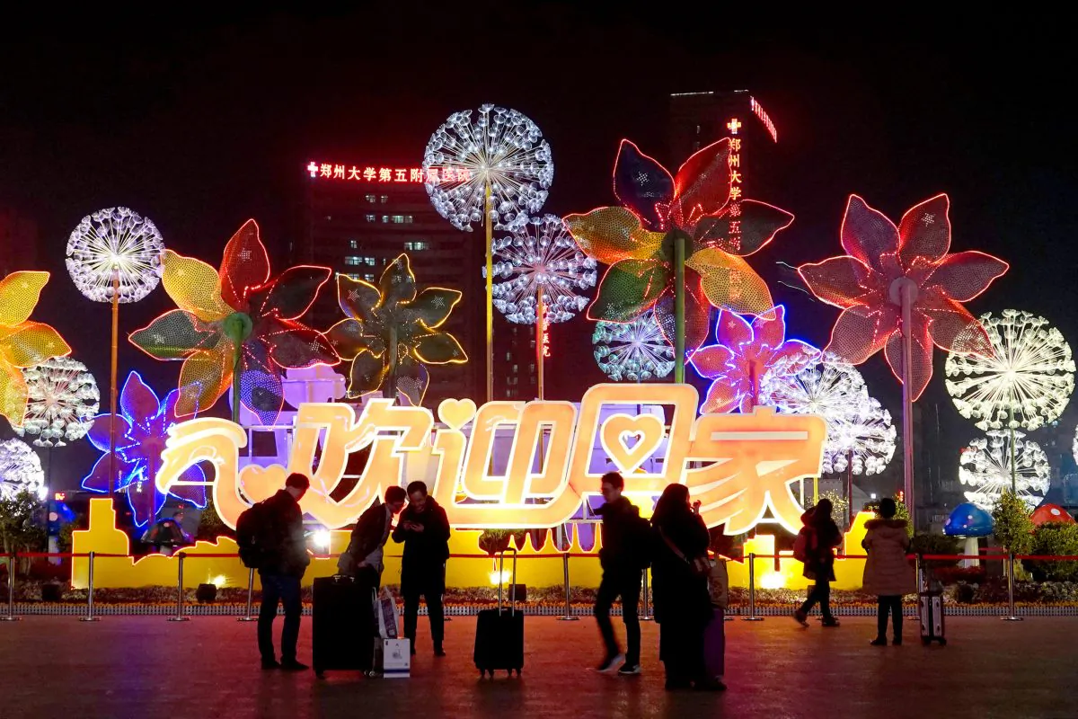 People are seen by an installation with Chinese characters reading, "Welcome Home," at the Zhengzhou Railway Station during the Lunar New Year travel rush in Henan Province, China on Jan. 29, 2019. (Reuters)
