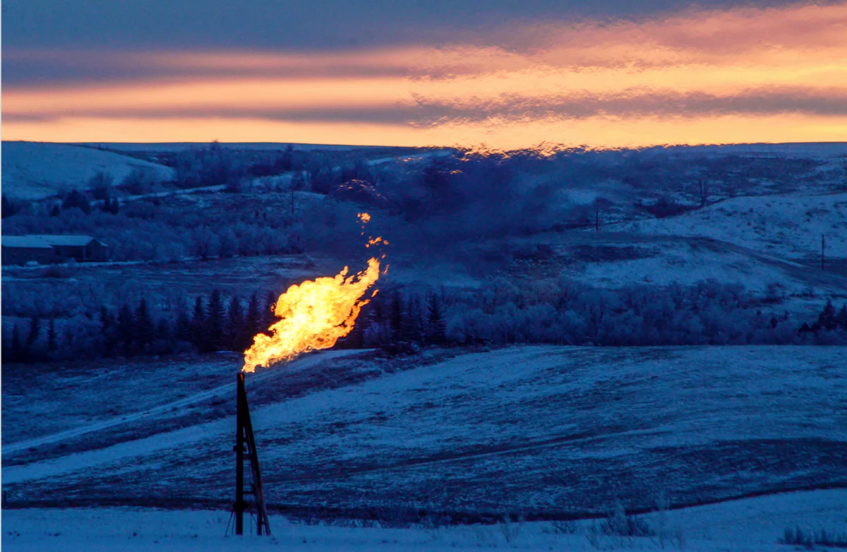 A natural gas flare on an oil well pad burns as the sun sets outside Watford City, N.D., on Jan. 21, 2016. (REUTERS/Andrew Cullen)