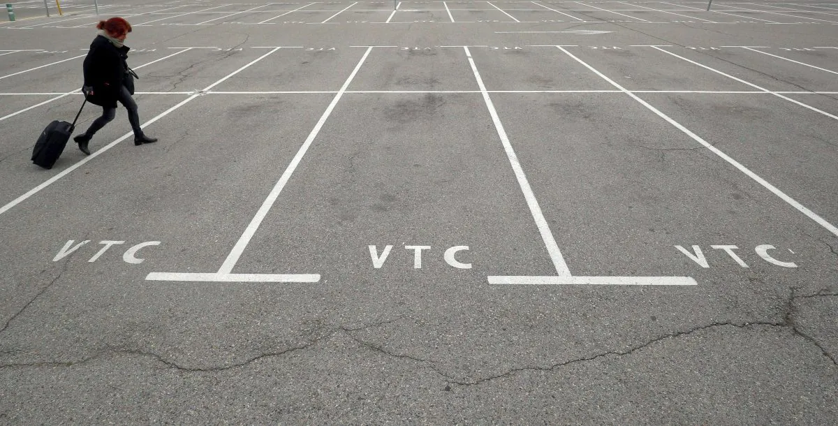 A woman walks past empty parking spots for ride-hailing services, known in Spain as VTC, at Barcelona airport, Spain, on Jan. 31, 2019. (Reuters/Albert Gea)