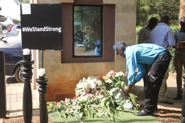 A security guard at 14 Riverside complex places flowers as memorial for the victims who perished during the attack on Dusit D2 Hotel and the 14 Riverside complex that took place in Nairobi, on Jan. 15, 2019. (Dominic Kirui for The Epoch Times)