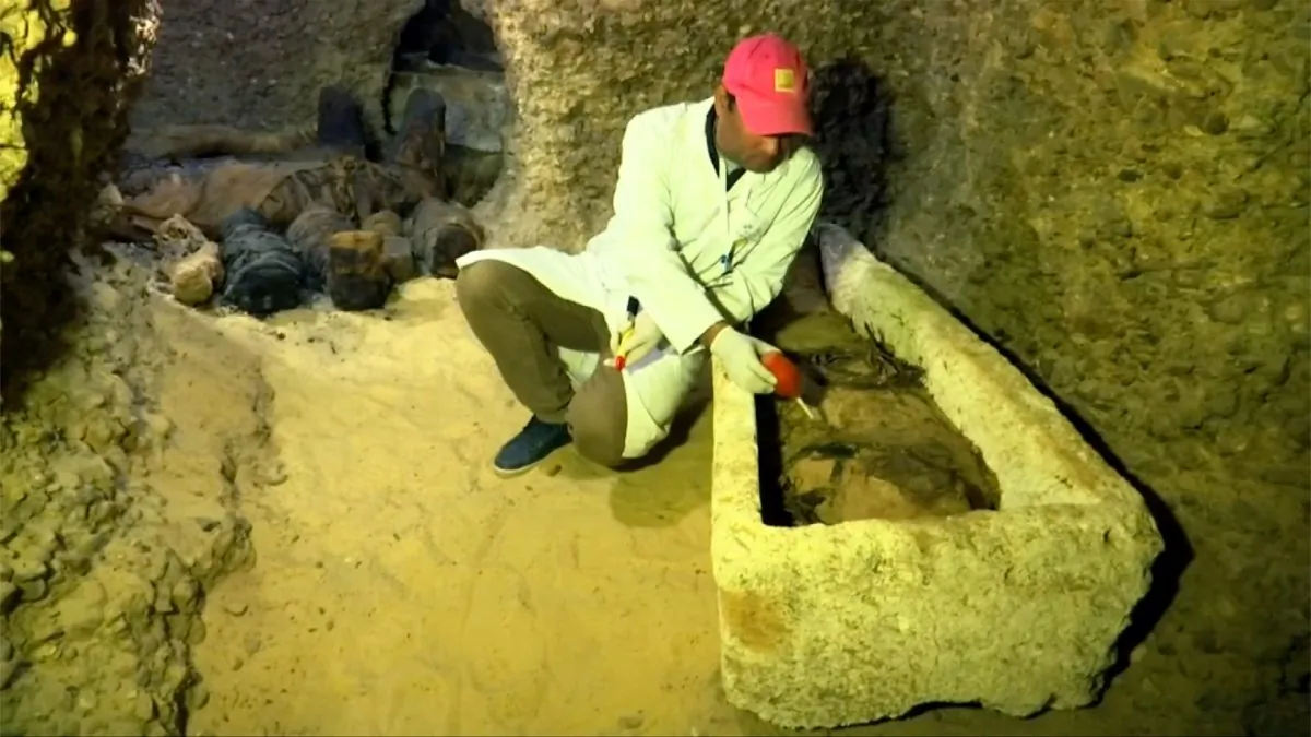 Archaeologist brushing mummy inside stone coffin in Tuna El-Gebel Region, Minya, Egypt, on Feb. 2, 2019. (Screenshot/Reuters)