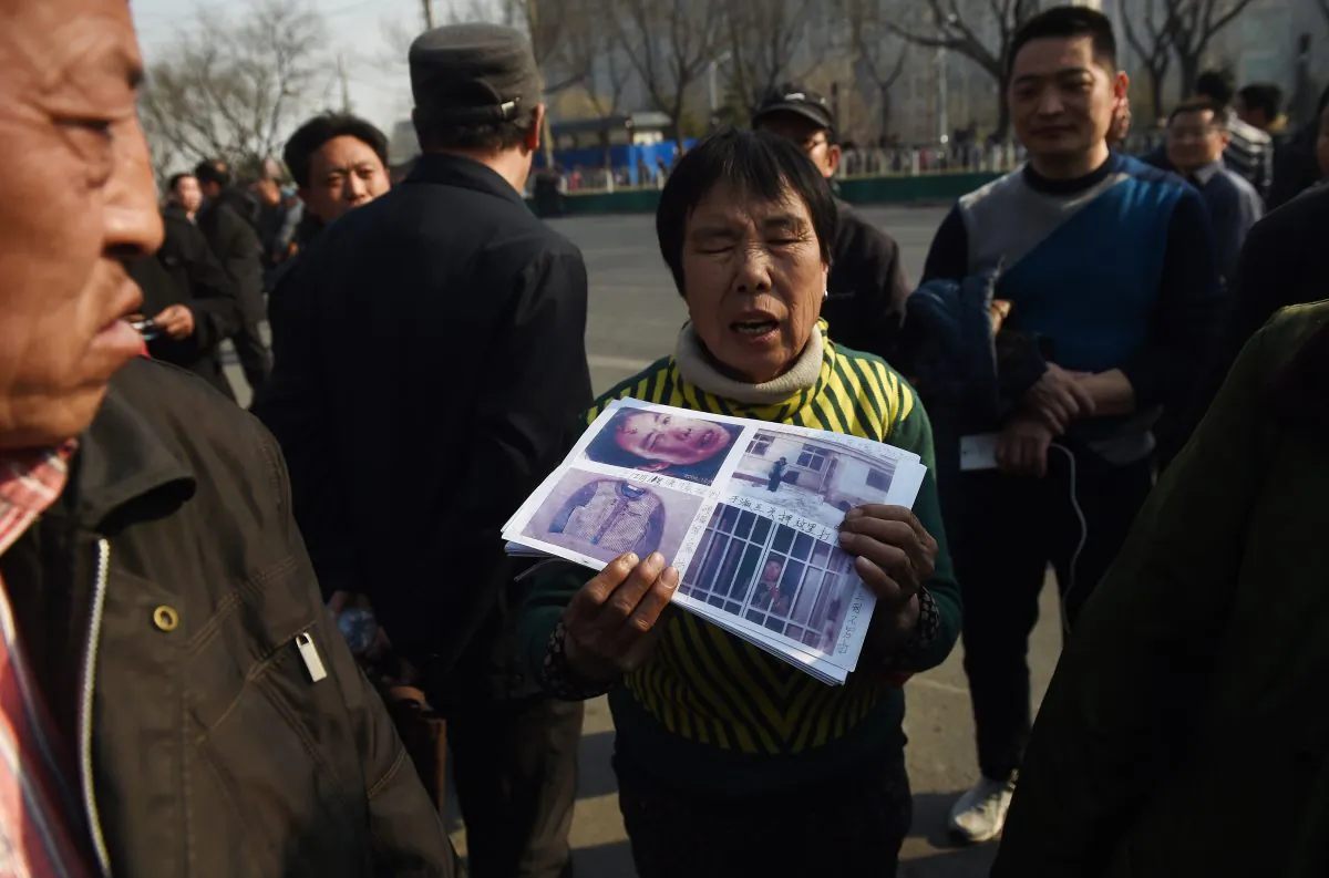 A petitioner holds photos of evidence in her grievance against local officials, outside a government petition office in Beijing on March 2, 2016. (Greg Baker/AFP/Getty Images)