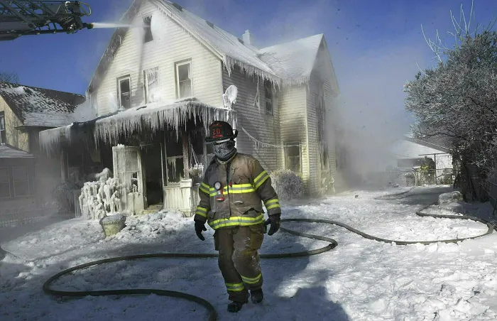 A firefighter walks past an ice-encrusted home after an early morning house fire in St. Paul, Minn., on Jan 30, 2019.  (Jean Pieri/Pioneer Press via AP, File)