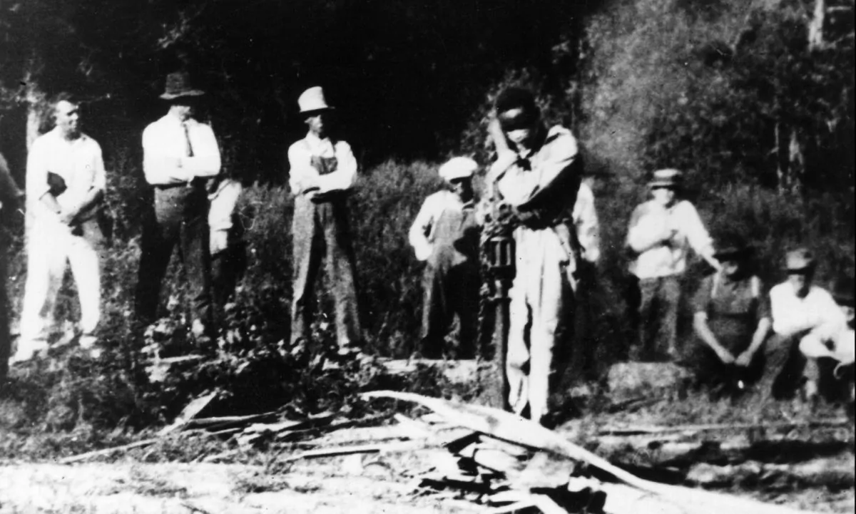 3rd October 1925: A gang of white men gather around J D Ivy, a black man they have blindfolded and tied to a stake in a forest in Georgia, USA. Hulton Archive/Getty Images