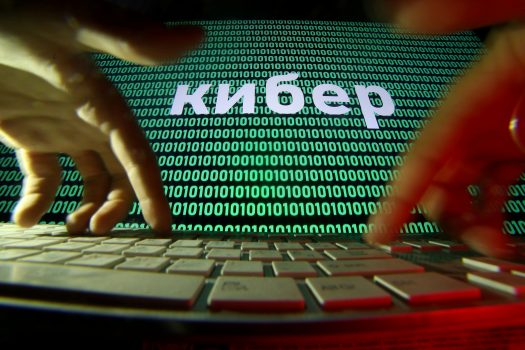 Hands on a keyboard in front of a displayed cyber code