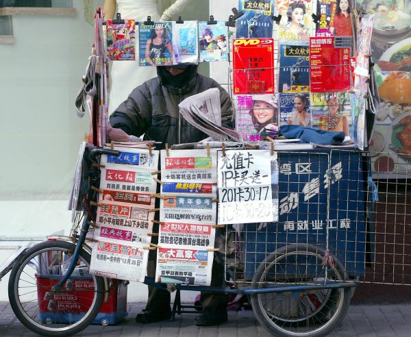 A man arranges newspaper at his newsstand in Shanghai.