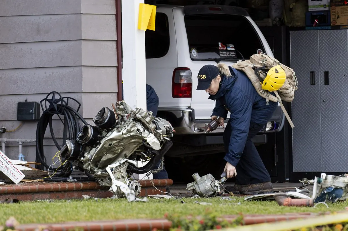 A National Transportation Safety Board worker takes a photo of an engine that came to rest against a house on Crestknoll Dr. in Yorba Linda, Calif on  February 4, 2019.  (Paul Bersebach/The Orange County Register via AP)