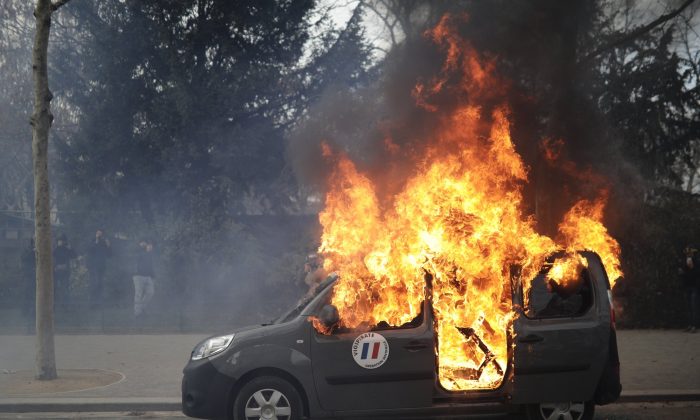 A burning command car belonging to France's anti-terror 'Vigipirate' squad, dubbed 'Operation Sentinelle', is pictured during a demonstration as yellow vests protesters keep pressure on French President Emmanuel Macron's government, for the 13th straight weekend of demonstrations, in Paris, France, on Feb. 9, 2019. (Kamil Zihnioglu/AP Photo)