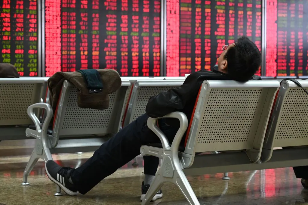 A man rests in front of screens showing stock prices at a securities company in Beijing on Jan. 21, 2019. (Greg Baker/AFP/Getty Image)