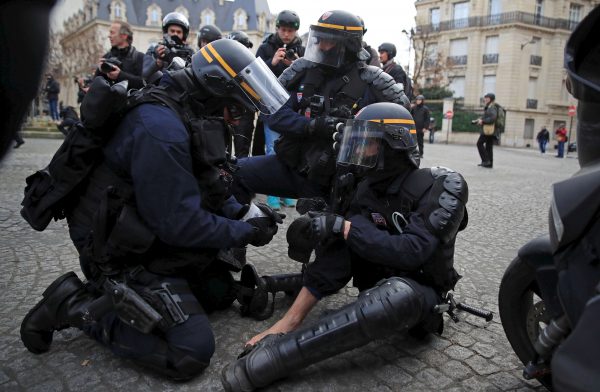 An injured policeman in riot gear is given help