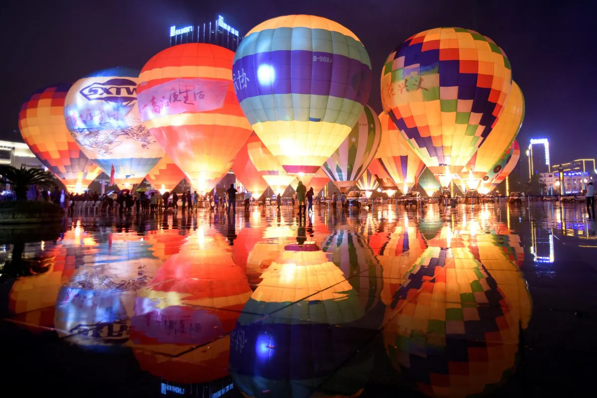 People look at hot air balloons decorating a plaza, during a tourism event in Qianxinan Buyei and Miao Autonomous Prefecture, Guizhou Province, China on Oc. 14, 2018. (China Daily via Reuters)