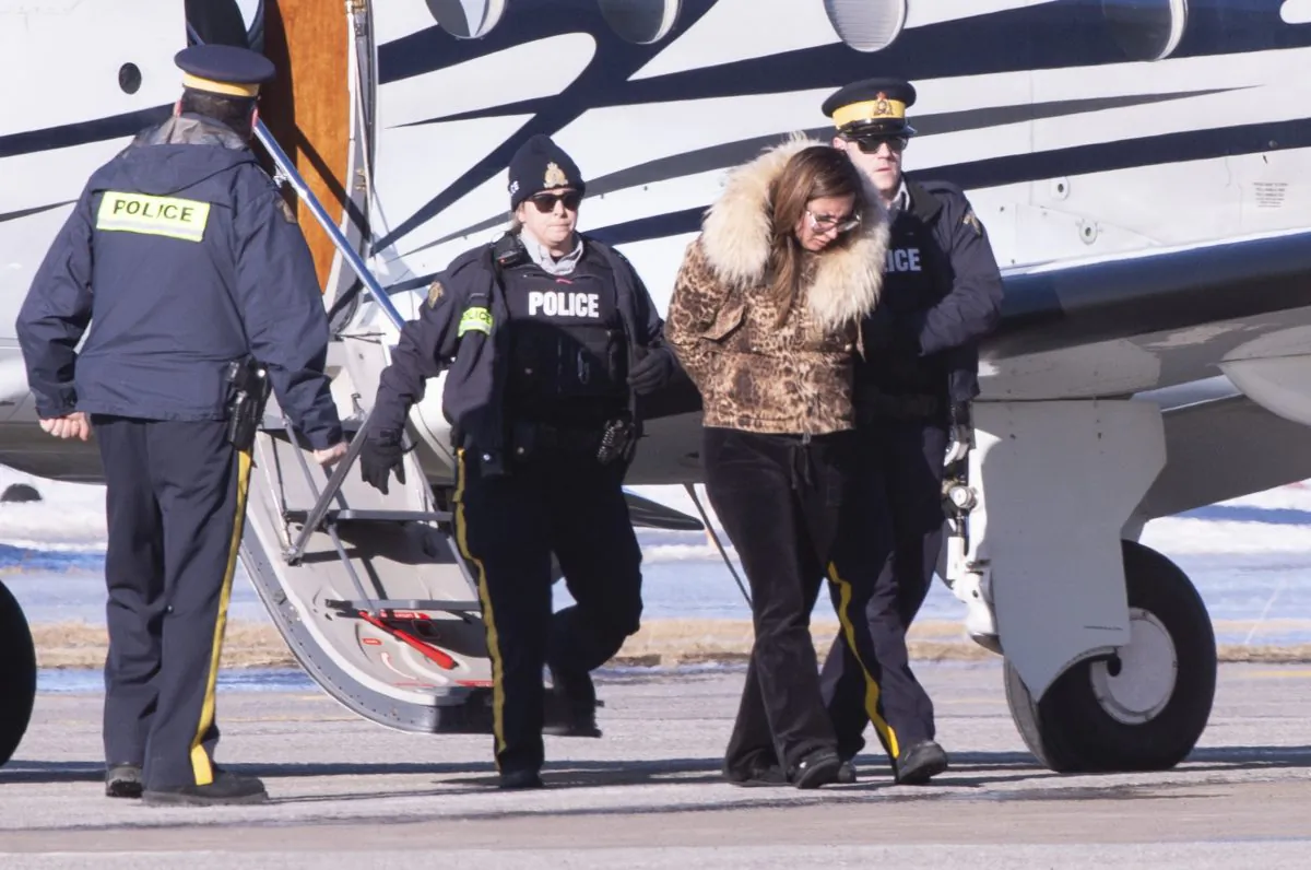 RCMP officers escort a female suspect in a money laundering network off an airplane in St-Hubert, Quebec, on Feb. 11, 2019. (The Canadian Press/Paul Chiasson)