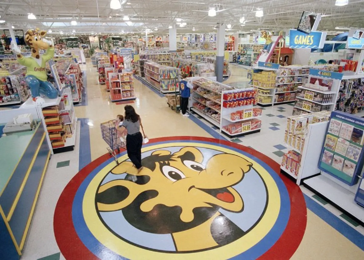 A woman pushes a shopping cart over a graphic of Toys R Us mascot Geoffrey the giraffe at the Toys R Us store in Raritan, N.J. on July 30, 1996. (AP Photo/Daniel Hulshizer, File)
