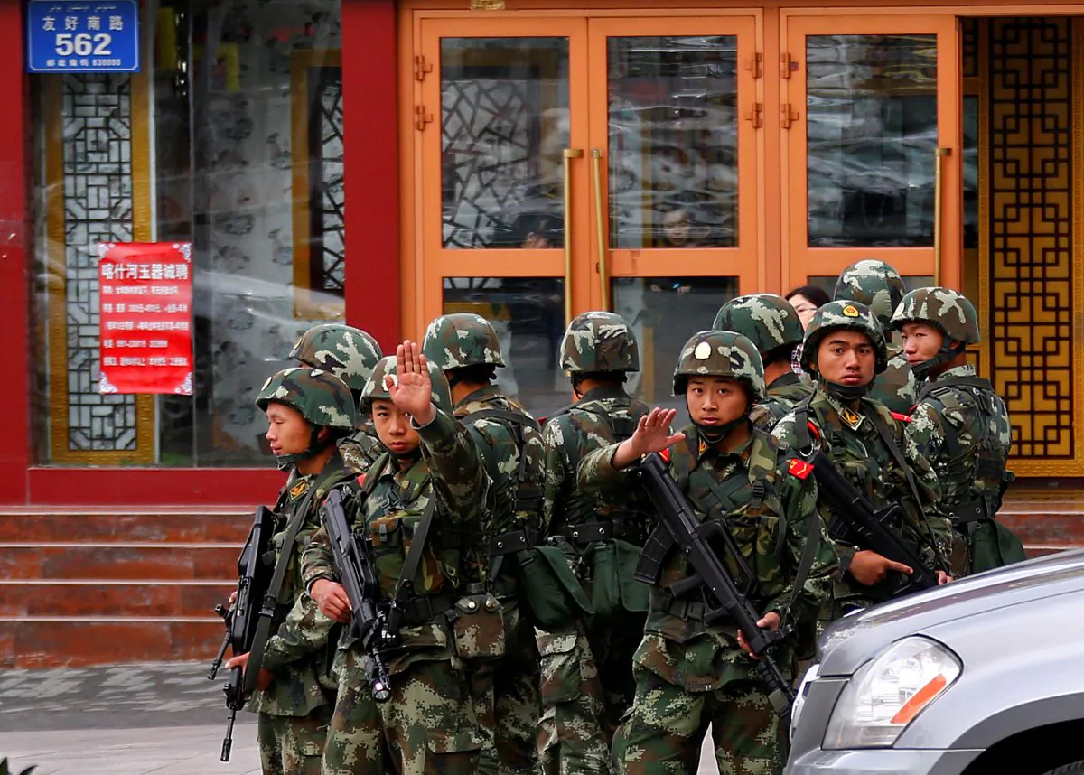Paramilitary policemen gesture to stop a photographer from taking pictures as they stand guard after an explosives attack hit downtown Urumqi in the Xinjiang Uyghur Autonomous Region on May 23, 2014. (Petar Kujundzic/Reuters)