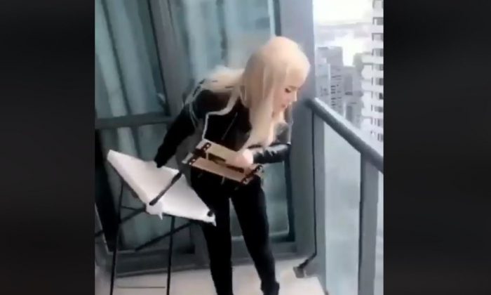 A woman identified by Toronto police as Marcella Zola throws a chair off a high-rise balcony in downtown Toronto. Zola surrendered to police on Feb. 13, 2019, and faced several charges. (Marcella Zola/Instagram)