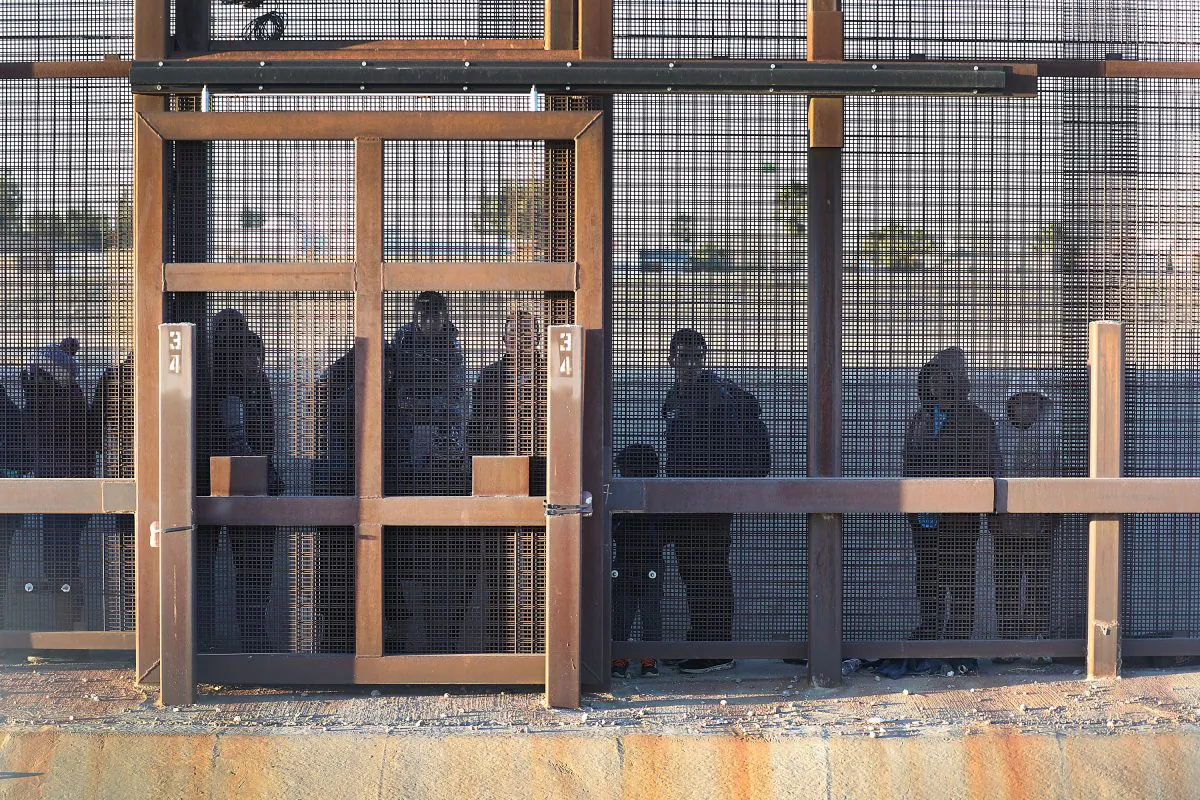 Migrants stand together along the U.S./Mexican border wall as they wait to turn themselves over to the U.S. Border Patrol in El Paso, Tex., on Feb. 12, 2019. (Joe Raedle/Getty Images)