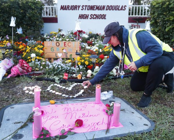 School crossing guard Wendy Behrend lights a candle at a memorial outside Marjory Stoneman Douglas High School