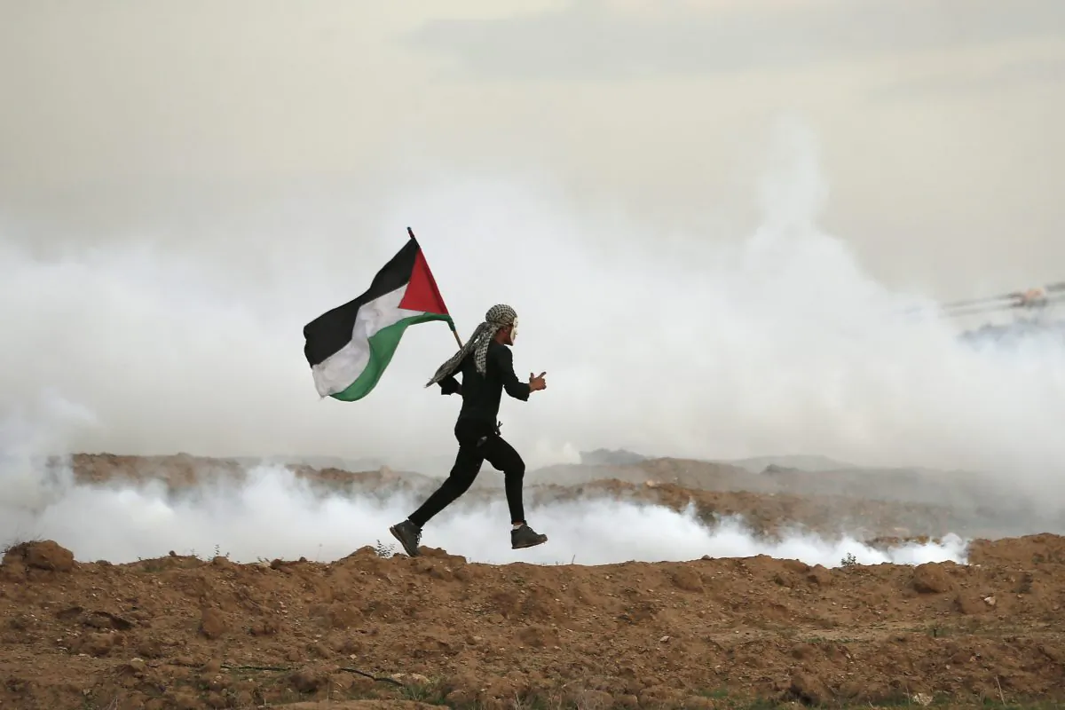 A man runs holding the Palestinian flag east of Gaza City near the Israeli border on Nov. 16, 2018. (Mahmud Hams/AFP/Getty Images)