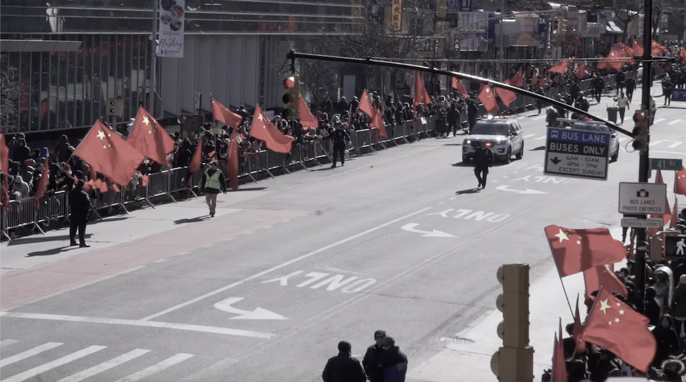 Dozens of people hold Chinese flags along Flushing's Main Street just before the start of the Lunar New Year Parade in Flushing, New York City on Feb. 9, 2019. (The Epoch Times)