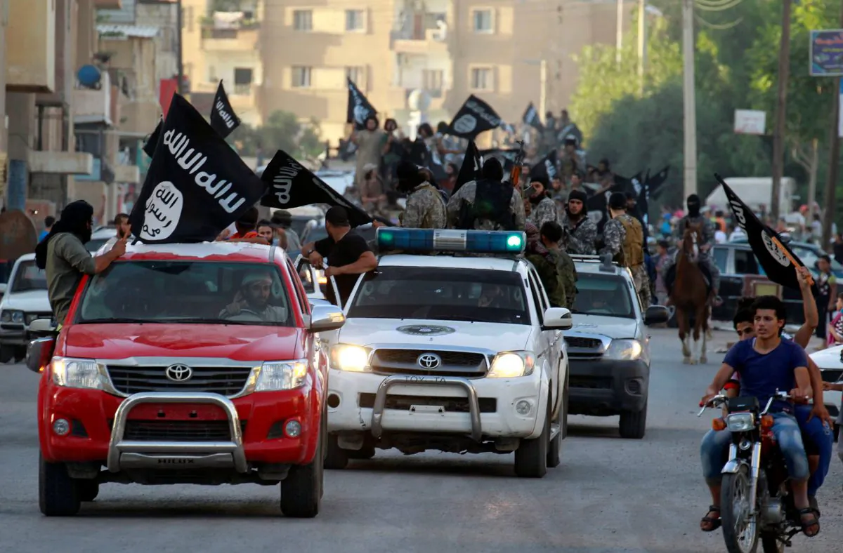 ISIS terrorists waving flags, travel in vehicles as they take part in a military parade along the streets of Syria's northern Raqqa province, on June 30, 2014.  (Stringer/Reuters)