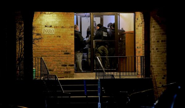 Investigators enter an apartment building in Aurora