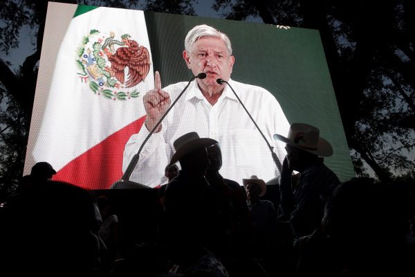 People watch Mexico's President Andres Manuel Lopez Obrador on a video screen during an event