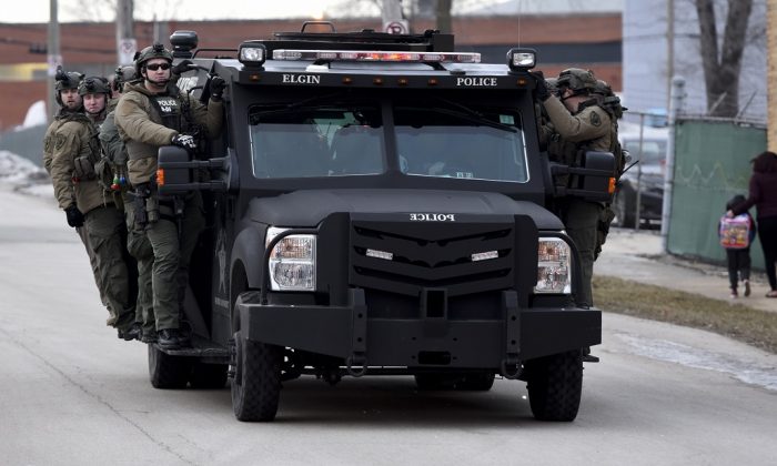 Police officers ride on a vehicle near the site of a shooting at a manufacturing plant in Aurora, Ill., that police said left several people dead, and several police officers wounded, on Feb. 15, 2019. (Matt Marton/AP Photo)