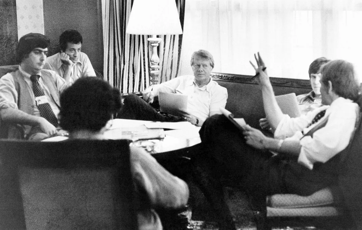 Jimmy Carter, center, meets with his staff, from back left, Pat Caddell, Jerry Rafshoon, his son, Chip and Jody Powell, and front left, Pat Anderson, at the Americana Hotel in New York on July 14, 1976. (AP Photo/Pool, File)