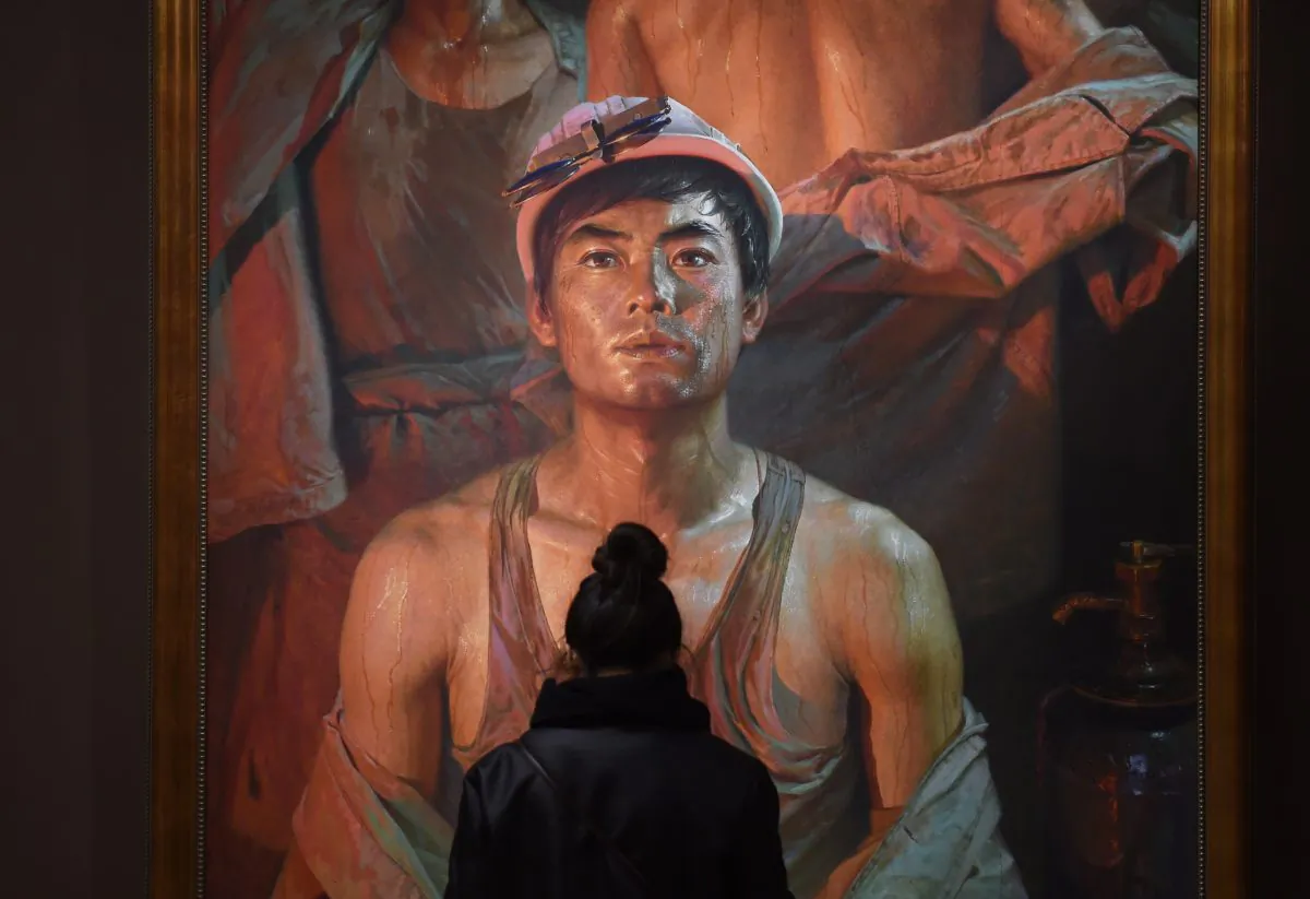 A visitor looks at a painting of a worker at an exhibition titled "Image of People" in Beijing on November 23, 2015. (GREG BAKER/AFP/Getty Images)