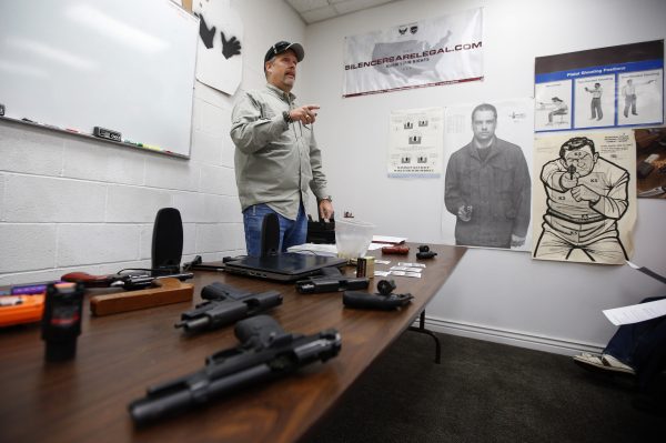 A gun instructor teaches a packed class