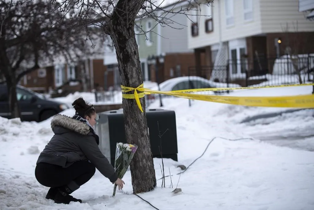 Local resident Jennifer Fuller places flowers at the scene outside of a house where a young girl was found dead in Brampton, Ont. on Feb. 15, 2019. (The Canadian Press/Andrew Ryan)