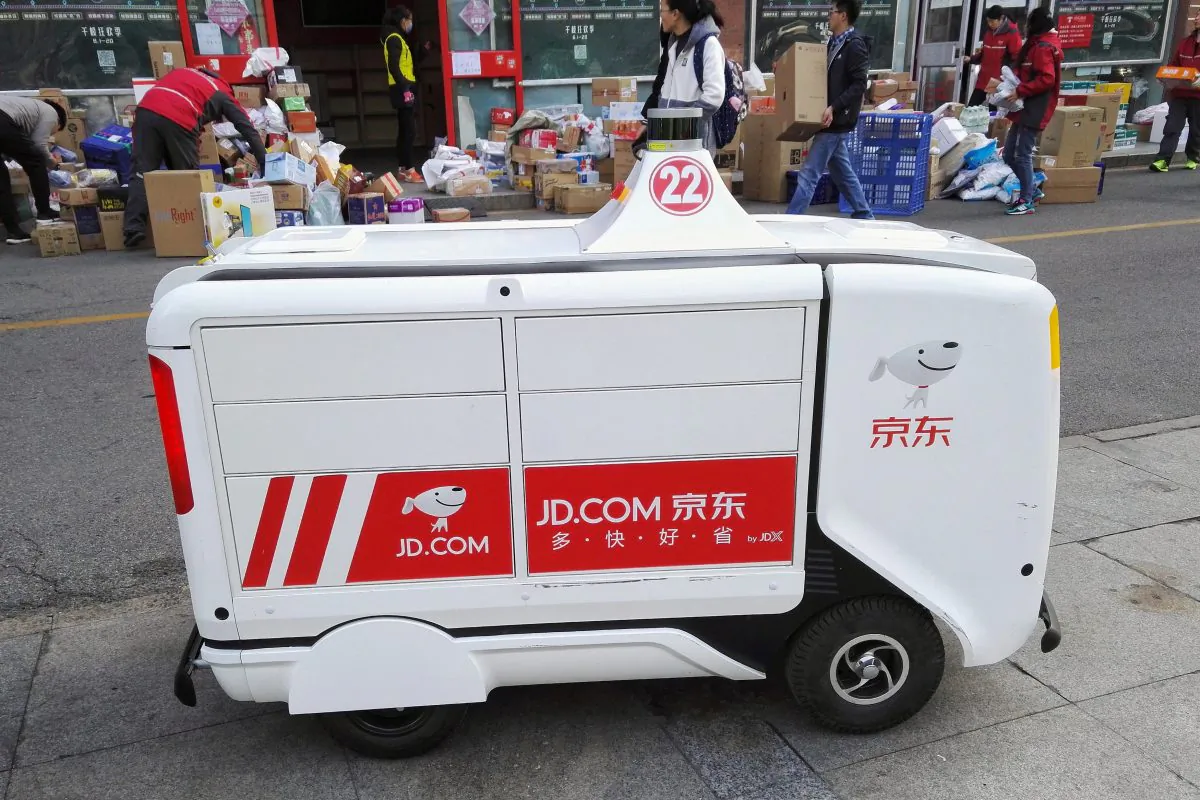 A JD.com driverless delivery robot is seen in front of parcels outside a JD.com logistics station at Renmin University of China a day after the Singles Day online shopping festival, in Beijing on Nov. 12, 2018. (Liu Hongsheng/Qianlong.com via Reuters)