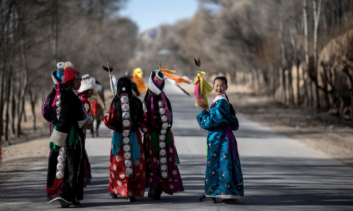 Girls dressed in traditional Tibetan costumes walking down a road after a festival to mark the Tibetan New Year celebrations in the village of Douhoulou, some 50 kms south of Guide on the Qinghai-Tibet Plateau on Feb. 25, 2018. (JOHANNES EISELE/AFP/Getty Images)